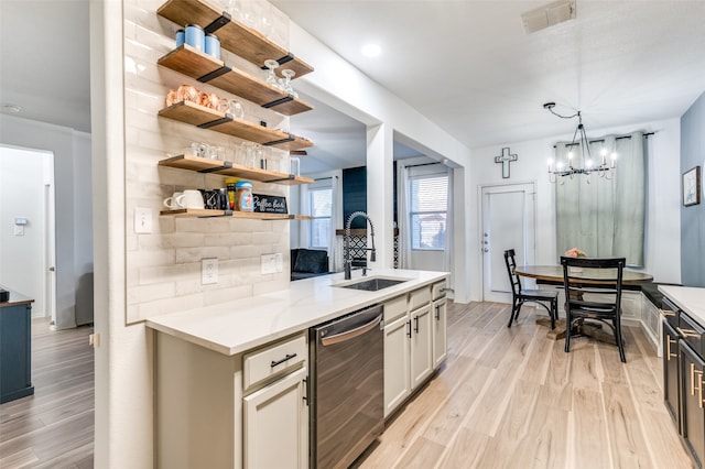 kitchen with light stone countertops, sink, dishwasher, hanging light fixtures, and light hardwood / wood-style floors