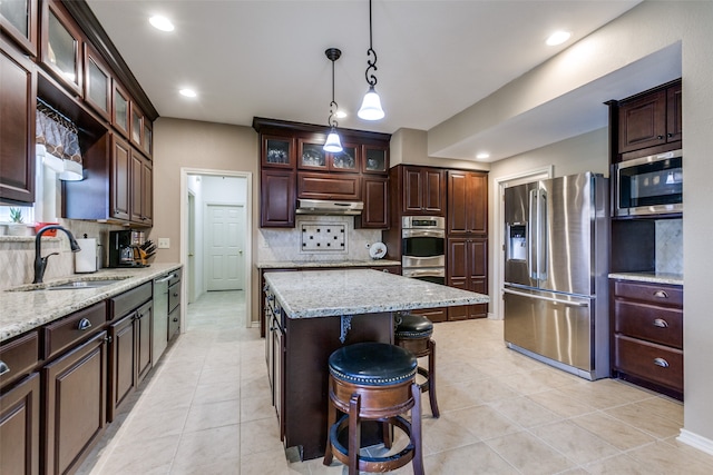 kitchen featuring tasteful backsplash, stainless steel appliances, sink, and a kitchen island