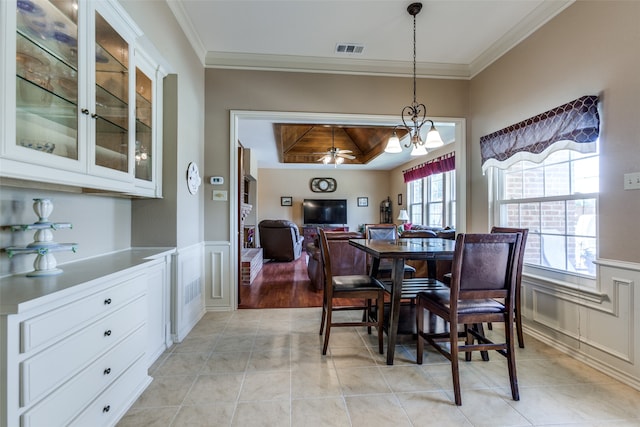 dining space featuring crown molding, light tile patterned flooring, and ceiling fan with notable chandelier