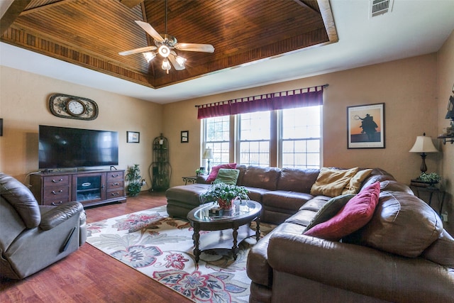 living room with hardwood / wood-style floors, a tray ceiling, and ceiling fan