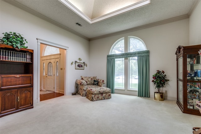 sitting room with a textured ceiling, crown molding, and light colored carpet