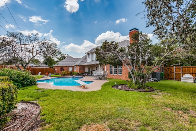 view of swimming pool with central AC, a diving board, a patio, and a lawn