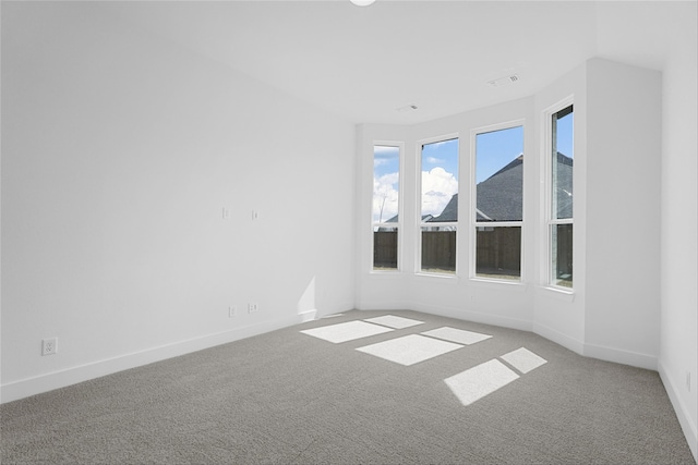 unfurnished room featuring carpet, visible vents, and baseboards