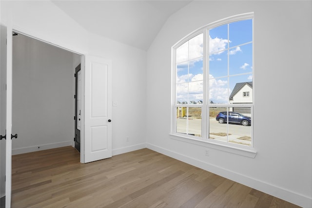 unfurnished room featuring lofted ceiling, light wood-type flooring, and baseboards