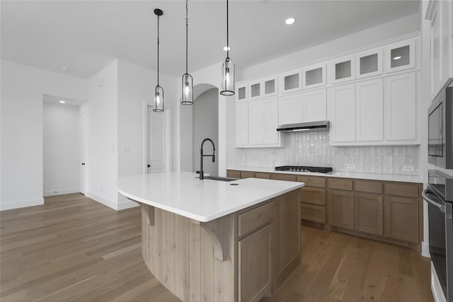 kitchen featuring light countertops, stainless steel microwave, backsplash, a sink, and oven