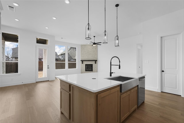 kitchen featuring visible vents, dishwasher, open floor plan, a brick fireplace, and a sink