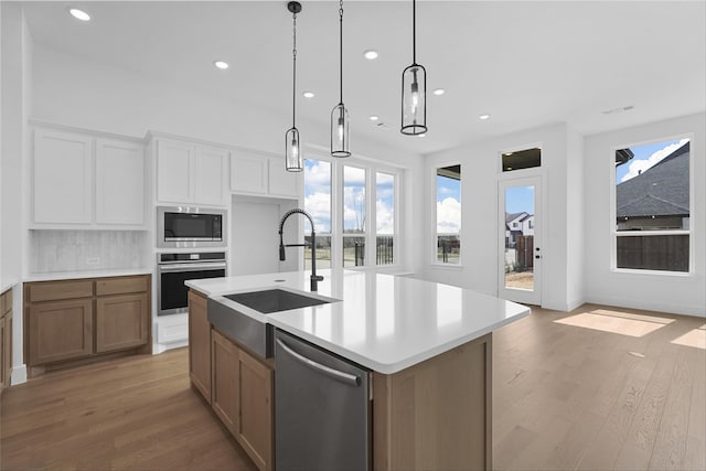 kitchen with stainless steel appliances, a healthy amount of sunlight, a sink, and light wood-style flooring