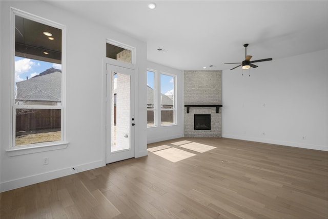 unfurnished living room featuring ceiling fan, recessed lighting, wood finished floors, baseboards, and a brick fireplace