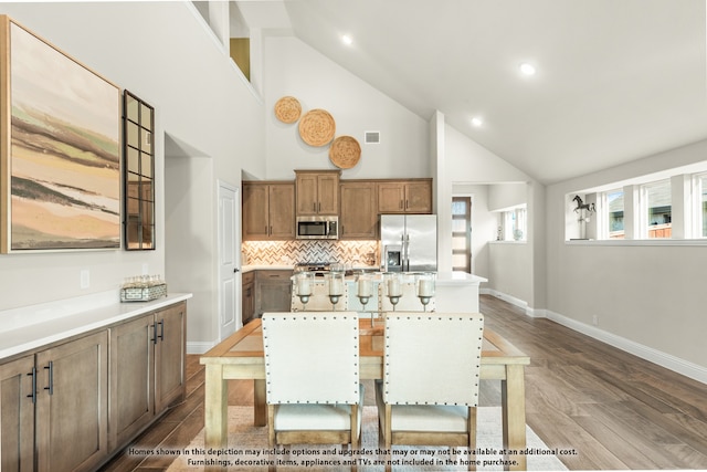 dining area with high vaulted ceiling and hardwood / wood-style flooring