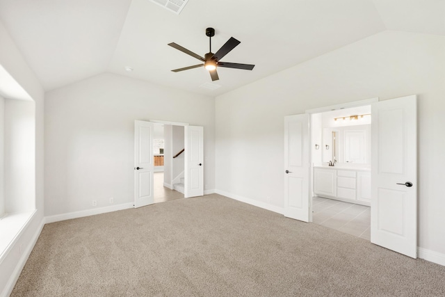 unfurnished bedroom featuring light colored carpet, ensuite bath, baseboards, lofted ceiling, and visible vents