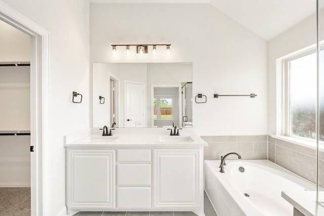 bathroom with a spacious closet, a sink, and a bath