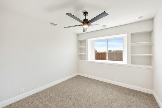 carpeted empty room featuring visible vents, baseboards, ceiling fan, and built in features