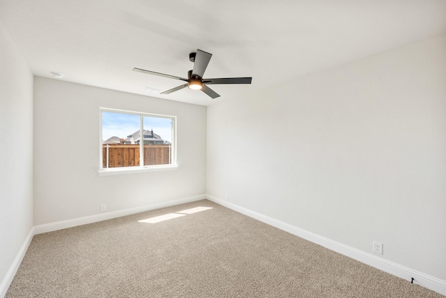 carpeted spare room featuring baseboards and ceiling fan