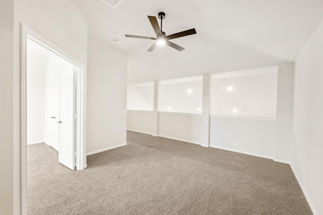 carpeted spare room with a ceiling fan, baseboards, and vaulted ceiling