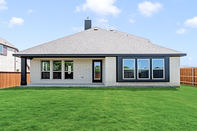 back of property featuring a fenced backyard, a lawn, and brick siding