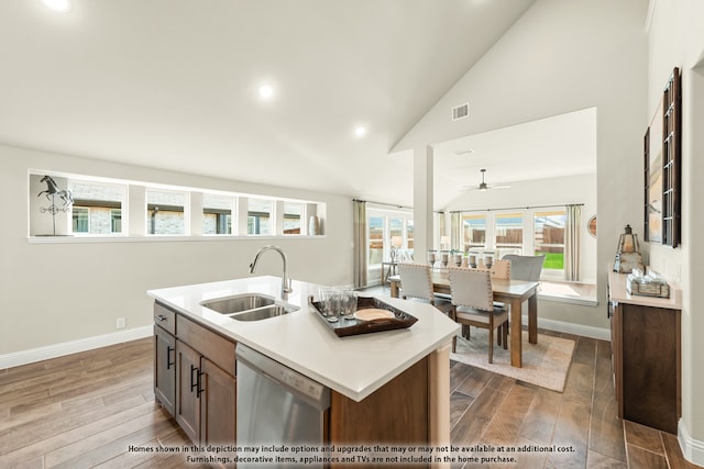 kitchen featuring dishwasher, sink, light wood-type flooring, and an island with sink