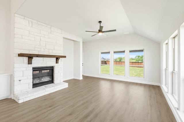 unfurnished living room featuring a ceiling fan, wood finished floors, vaulted ceiling, and a fireplace