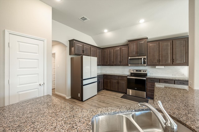 kitchen with sink, vaulted ceiling, dark brown cabinets, appliances with stainless steel finishes, and light wood-type flooring