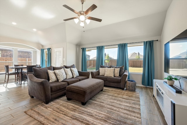 living room with lofted ceiling, ceiling fan, and light wood-type flooring