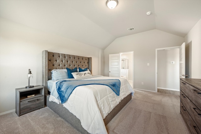 bedroom with ensuite bathroom, lofted ceiling, and light colored carpet