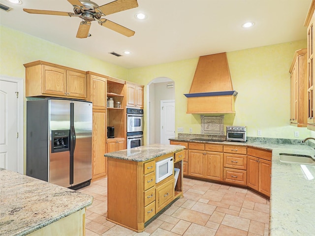 kitchen featuring light stone countertops, sink, stainless steel appliances, range hood, and a kitchen island