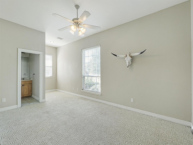 unfurnished bedroom with ceiling fan, light carpet, and ensuite bath