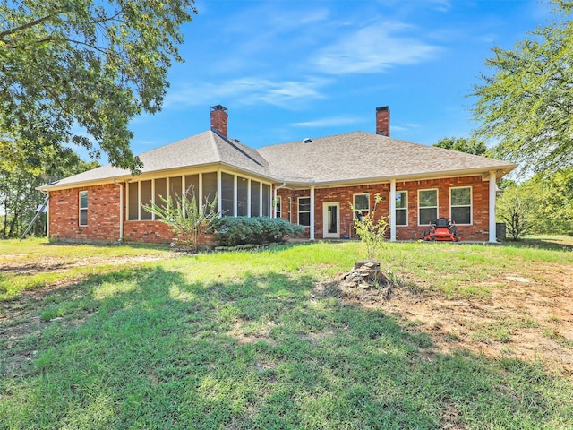 rear view of house with a lawn and a sunroom