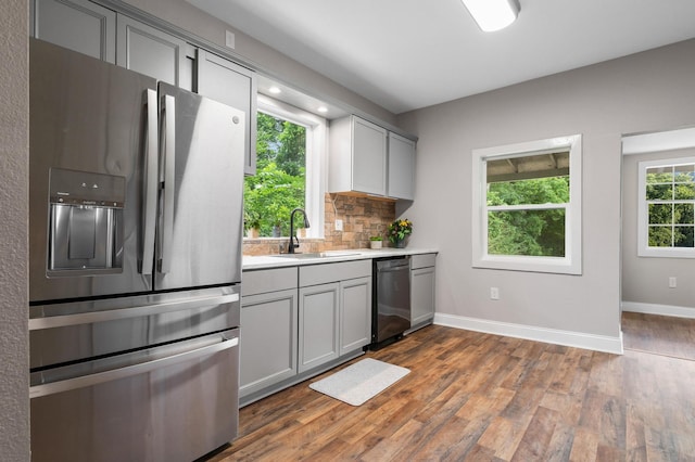 kitchen with gray cabinets, appliances with stainless steel finishes, light countertops, a sink, and dark wood-style floors