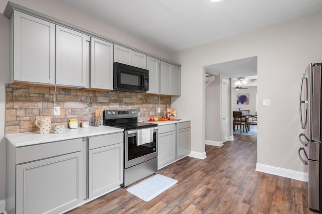 kitchen with gray cabinetry, ceiling fan, dark wood-type flooring, stainless steel appliances, and tasteful backsplash