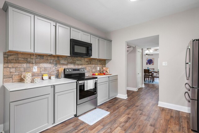 kitchen with dark wood finished floors, tasteful backsplash, gray cabinets, stainless steel appliances, and baseboards