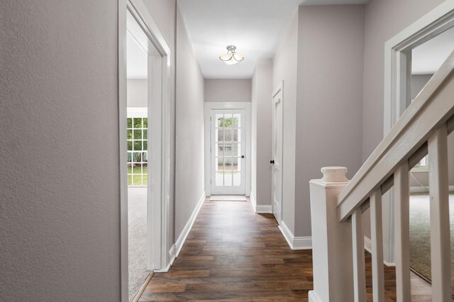 hallway featuring dark wood finished floors and baseboards
