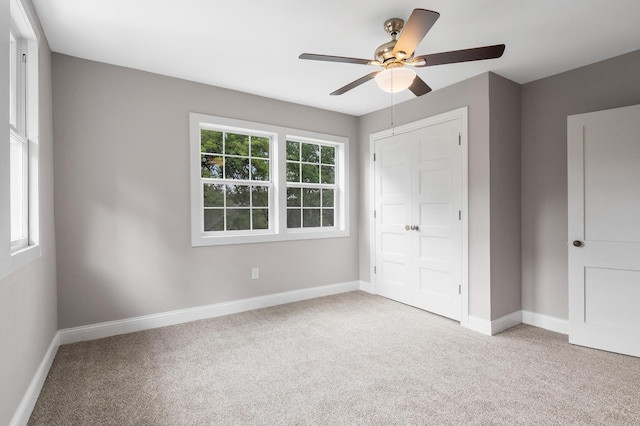 unfurnished bedroom featuring ceiling fan, light colored carpet, and multiple windows