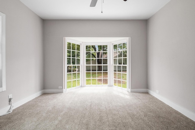 unfurnished room featuring a ceiling fan, carpet floors, and baseboards