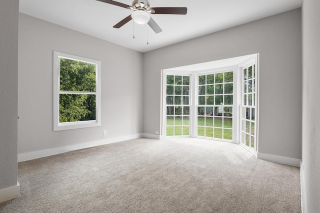 carpeted empty room with ceiling fan and baseboards