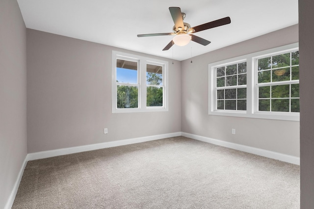 carpeted spare room with ceiling fan and baseboards