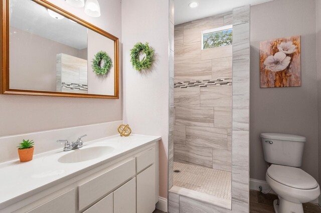 bathroom with recessed lighting, vanity, a walk in shower, toilet, and baseboards