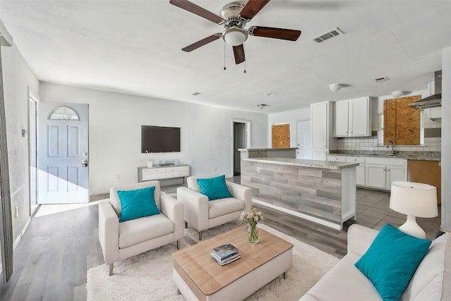 living room with sink, ceiling fan, and light hardwood / wood-style flooring