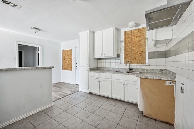 kitchen with light tile patterned flooring, white cabinetry, tasteful backsplash, and sink