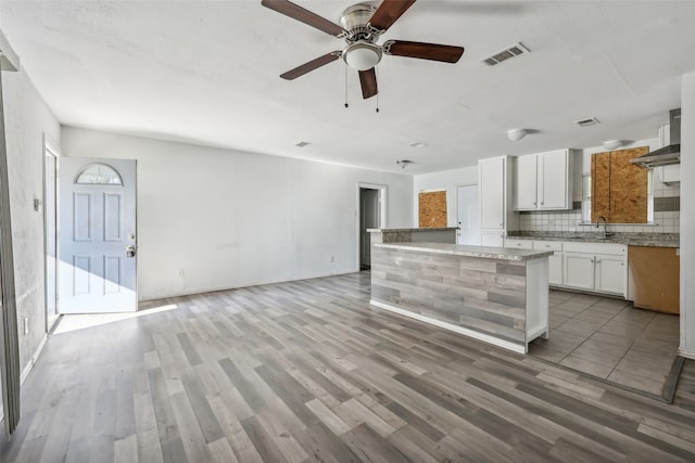 kitchen featuring decorative backsplash, ceiling fan, white cabinetry, light hardwood / wood-style floors, and sink