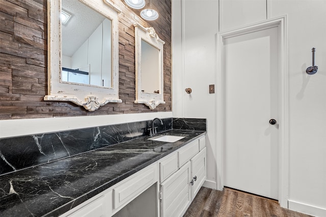 bathroom with vanity, hardwood / wood-style floors, a textured ceiling, and wood walls