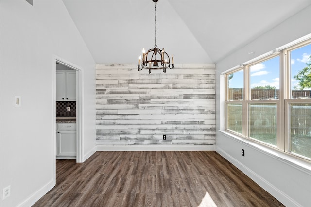 unfurnished dining area featuring an inviting chandelier, dark wood-type flooring, and vaulted ceiling