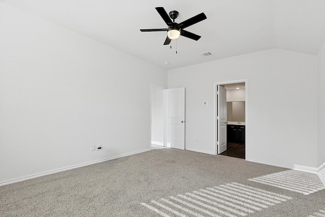 unfurnished bedroom featuring dark colored carpet, ensuite bathroom, vaulted ceiling, and ceiling fan