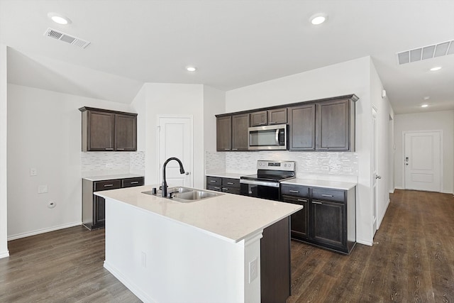 kitchen with appliances with stainless steel finishes, sink, backsplash, dark wood-type flooring, and a kitchen island with sink