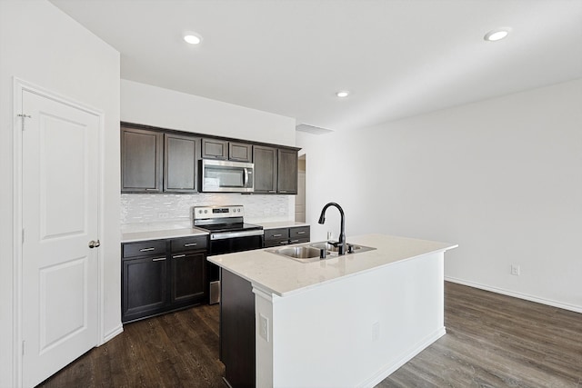 kitchen with decorative backsplash, dark hardwood / wood-style floors, an island with sink, sink, and appliances with stainless steel finishes