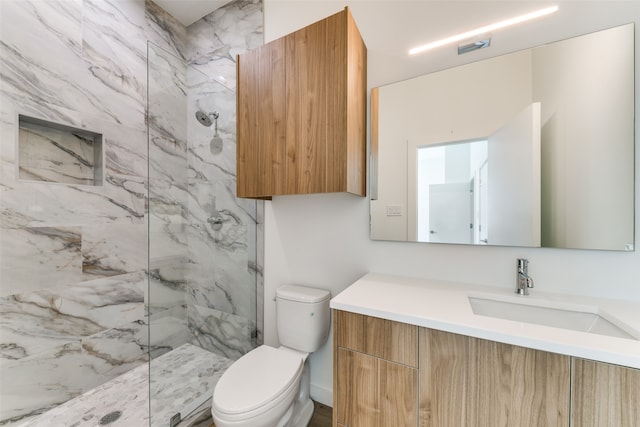 bathroom featuring toilet, vanity, and tiled shower