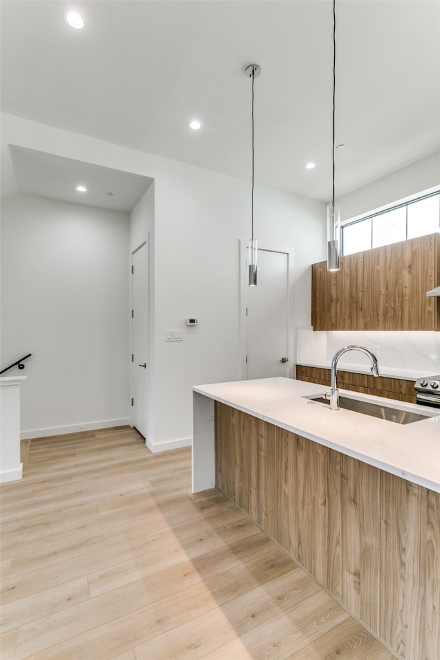 kitchen with light hardwood / wood-style flooring, stainless steel electric range, decorative light fixtures, and sink