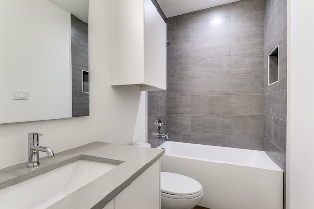 full bathroom featuring tiled shower / bath, vanity, and toilet