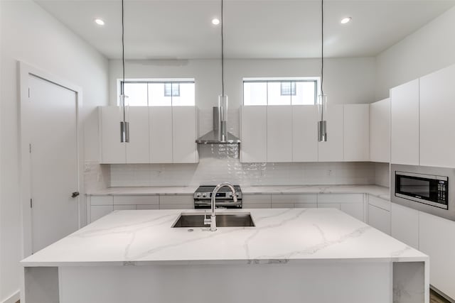 kitchen featuring a center island with sink, appliances with stainless steel finishes, pendant lighting, and white cabinets