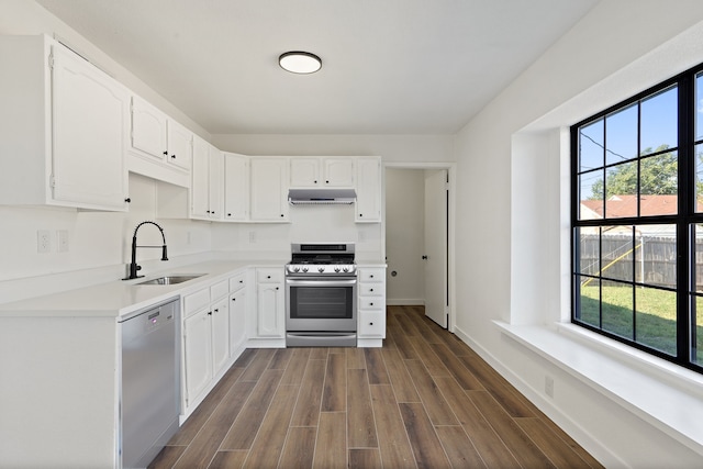 kitchen with appliances with stainless steel finishes, sink, dark hardwood / wood-style flooring, white cabinetry, and a wealth of natural light