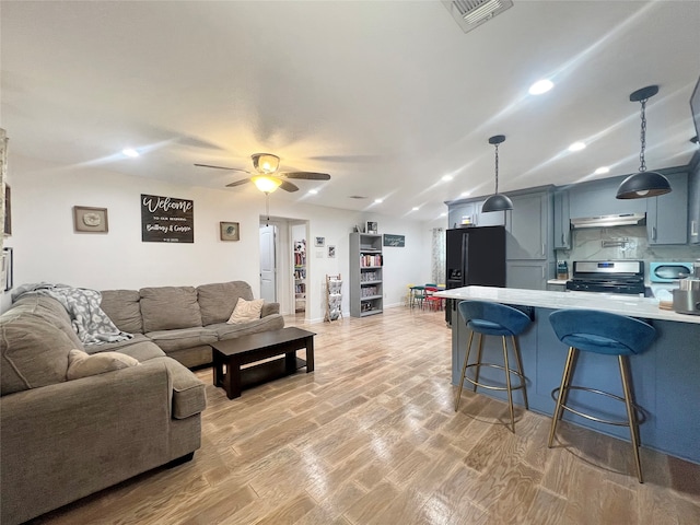 living room with ceiling fan, lofted ceiling, and light hardwood / wood-style flooring